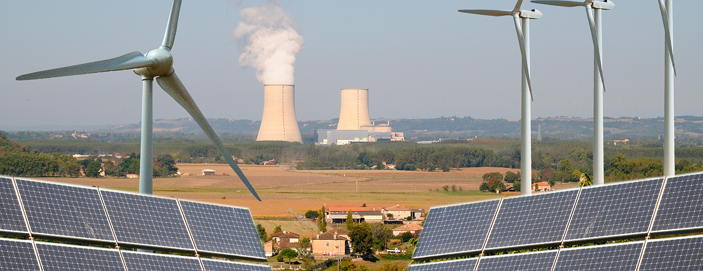 Vue de panneaux solaires et d’éoliennes devant une centrale nucléaire
