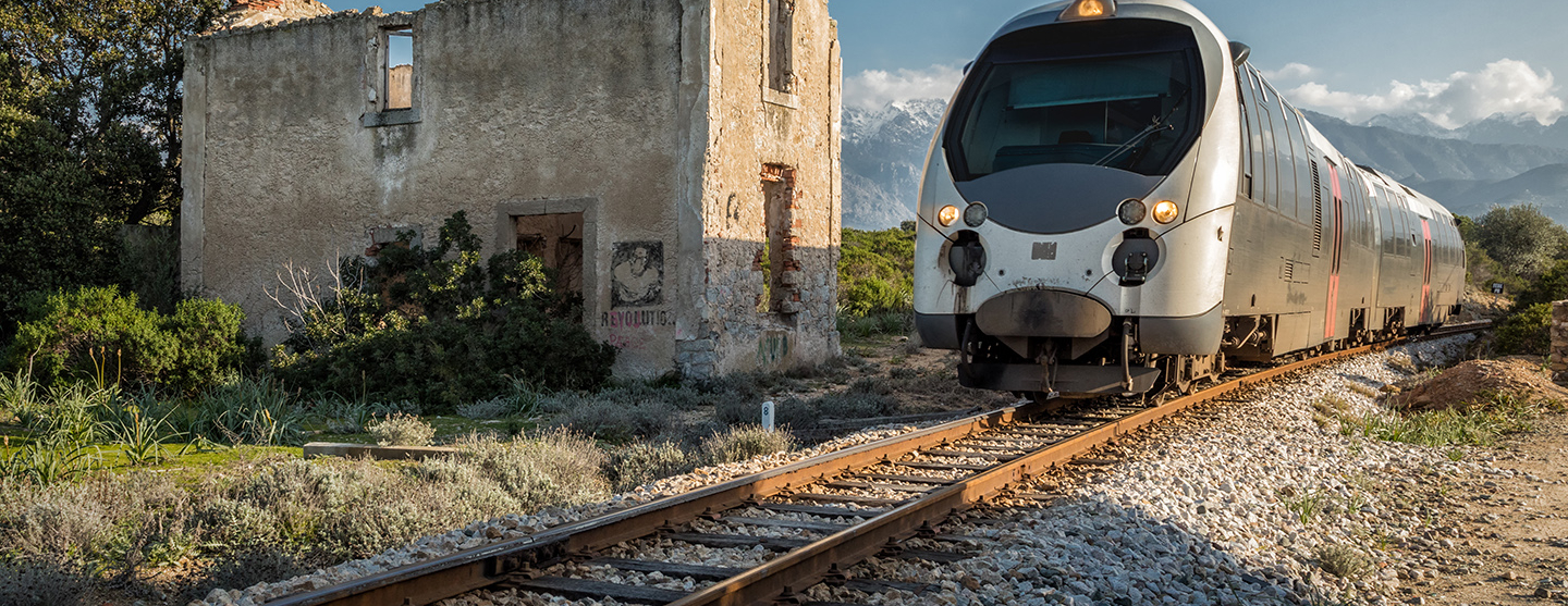 Train passant devant la station délabrée de Lumio en Corse