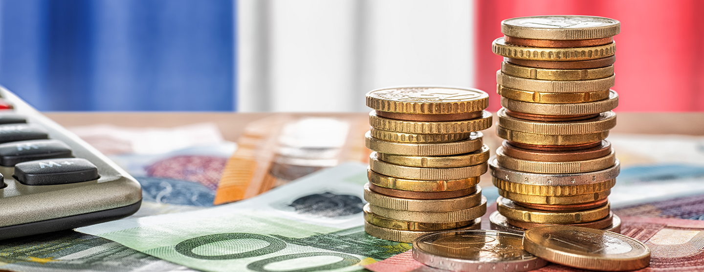 Vue de billets et piles de pièces de monnaie sur une table devant le drapeau français