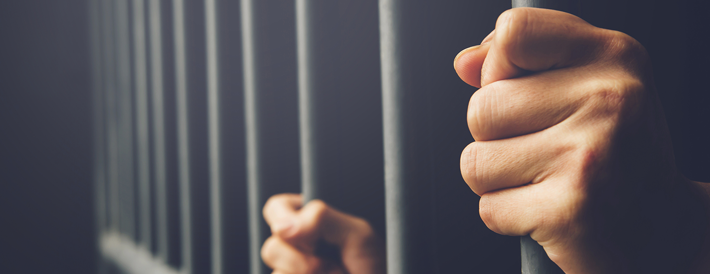 Mains de prisonniers dépassant de grilles de cellules