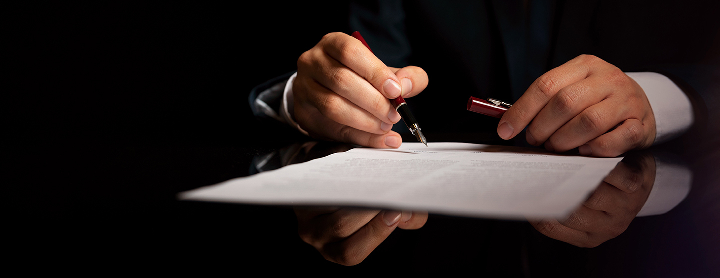 Personne assise à un bureau écrivant sur une feuille blanche