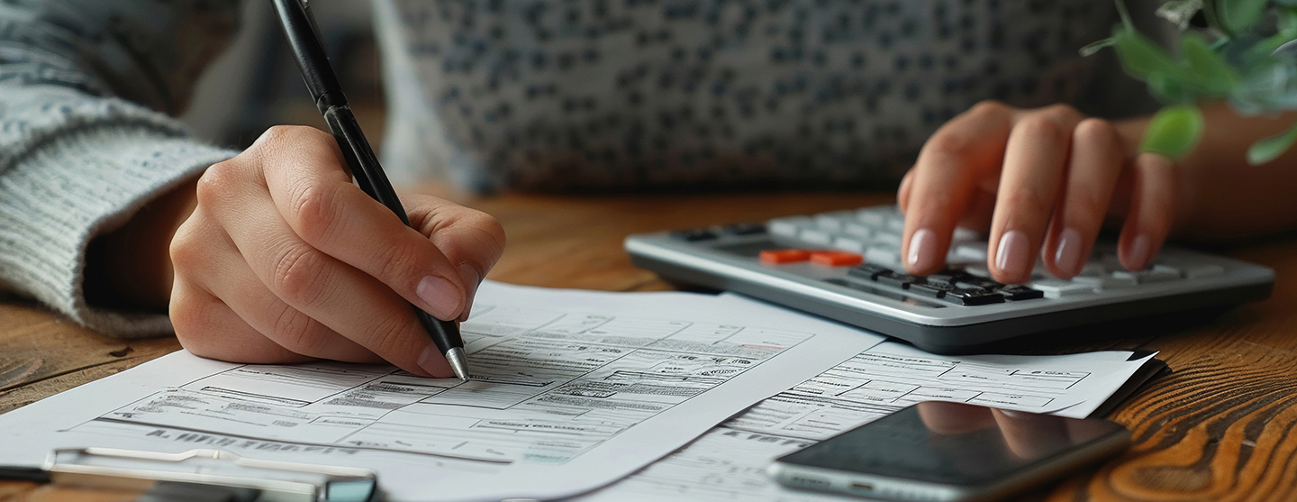 Personne assise à un bureau, écrivant sur une feuille de papier